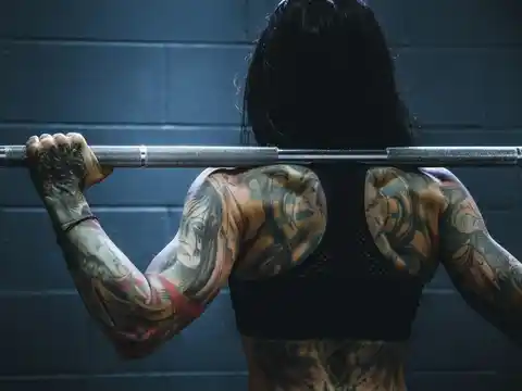 A tattooed woman lifts a barbell