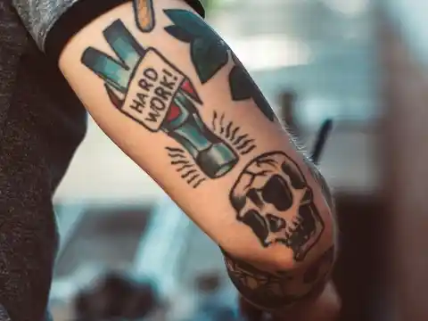 A tattoo on the back of the arm saying 'hard work'