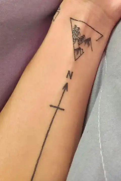 A tattoo of compass with an arrow pointing north