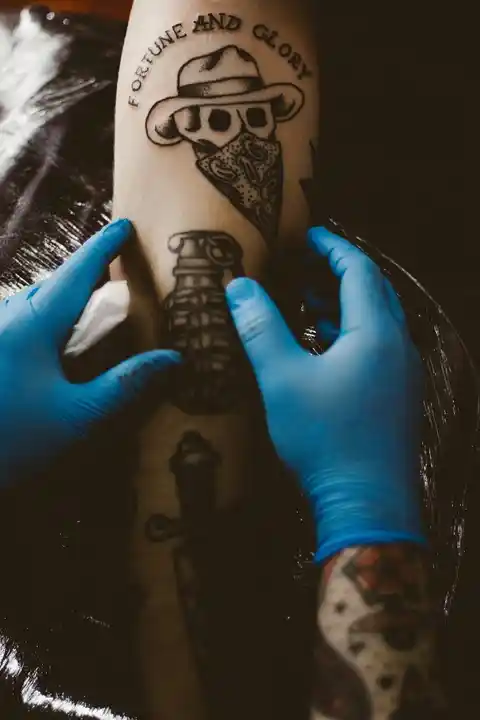 A tattoo artist inspects a tattoo