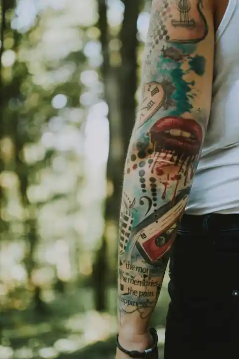 A colourful sleeve tattoo on the back of an arm with a mouth on it