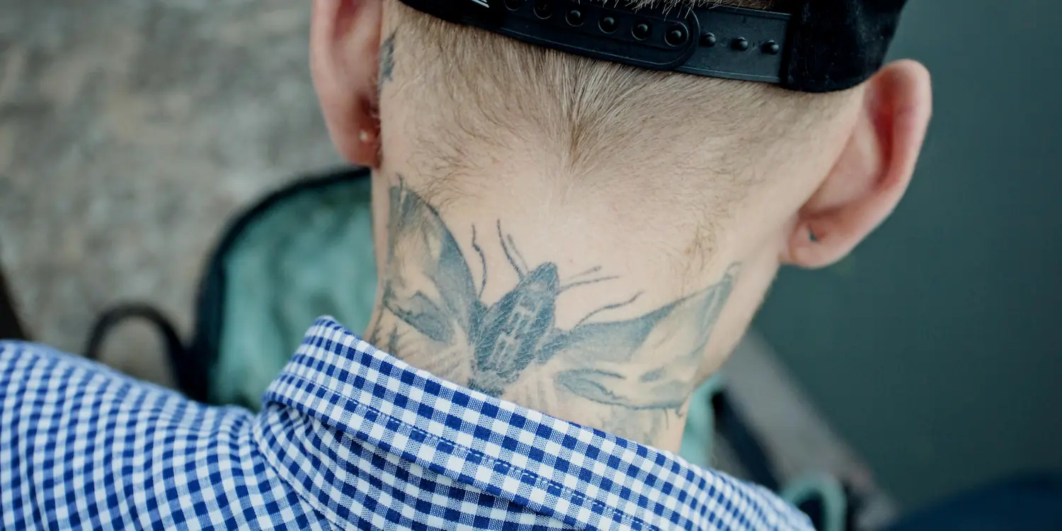 A tattoo of an insect on the back of a man's neck