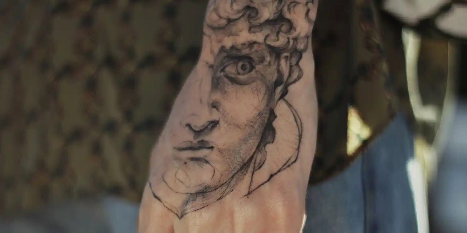 A realistic face tattoo, on a hand